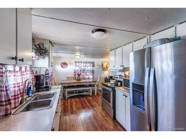 a kitchen that has a lot of cabinets stainless steel appliances and wooden floor