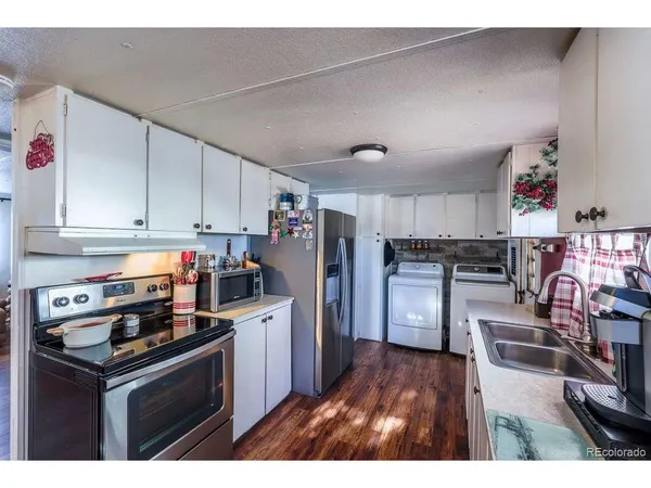 a kitchen with stainless steel appliances granite countertop a refrigerator a stove a sink dishwasher and white cabinets with wooden floor