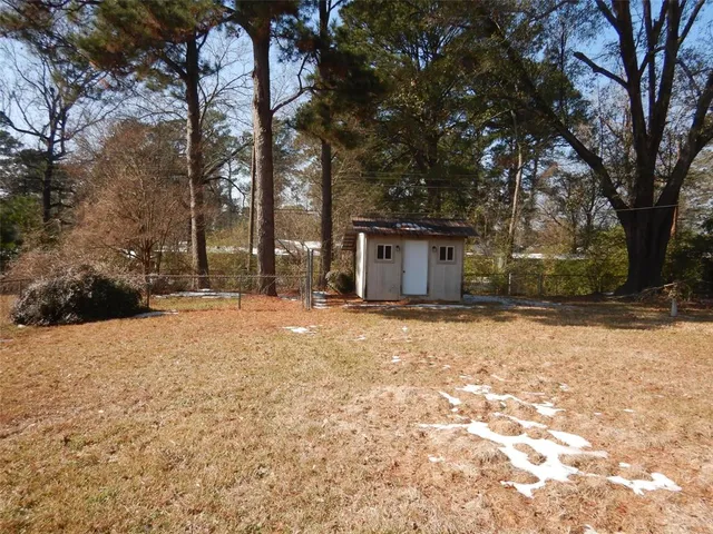 a backyard of a house with large trees and a barn