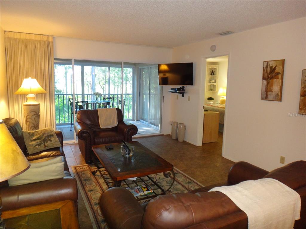 4493 Longmeadow, Unit 76 Sarasota, FL 34235 - Photo 14 of 24 a living room with furniture a flat screen tv and a floor to ceiling window