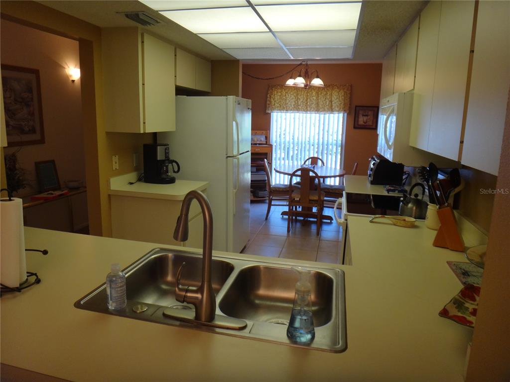 4493 Longmeadow, Unit 76 Sarasota, FL 34235 - Photo 7 of 24 a kitchen with sink a refrigerator and chairs