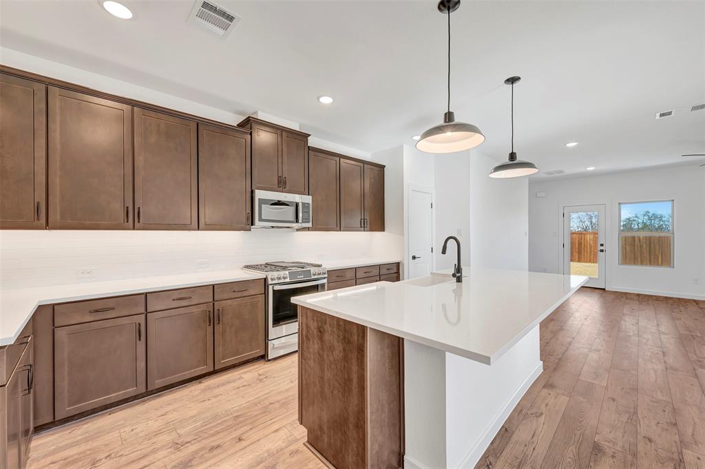 2217 Maple Ridge Drive Van Alstyne, TX 75495 - Photo 12 of 38 a kitchen with kitchen island a sink stainless steel appliances and cabinets