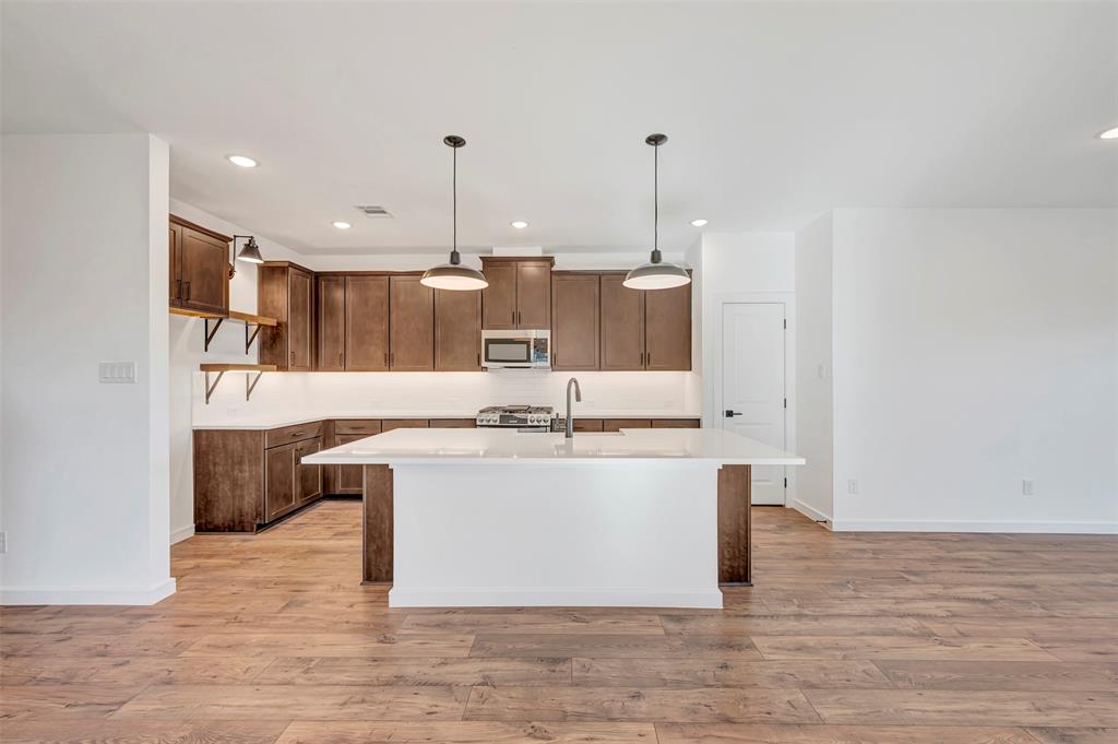2217 Maple Ridge Drive Van Alstyne, TX 75495 - Photo 13 of 38 a large kitchen with stainless steel appliances a large counter top a stove a sink and a refrigerator