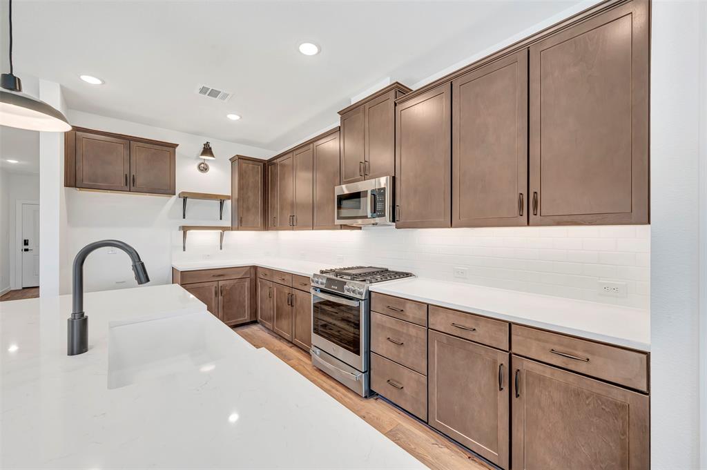 2217 Maple Ridge Drive Van Alstyne, TX 75495 - Photo 16 of 38 a kitchen with stainless steel appliances granite countertop a white stove top oven and sink