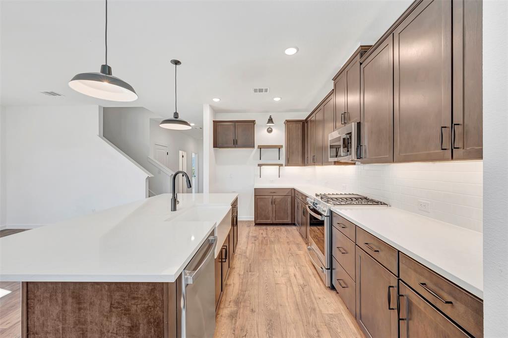 2217 Maple Ridge Drive Van Alstyne, TX 75495 - Photo 17 of 38 a kitchen with stainless steel appliances granite countertop a sink a stove and a wooden floors