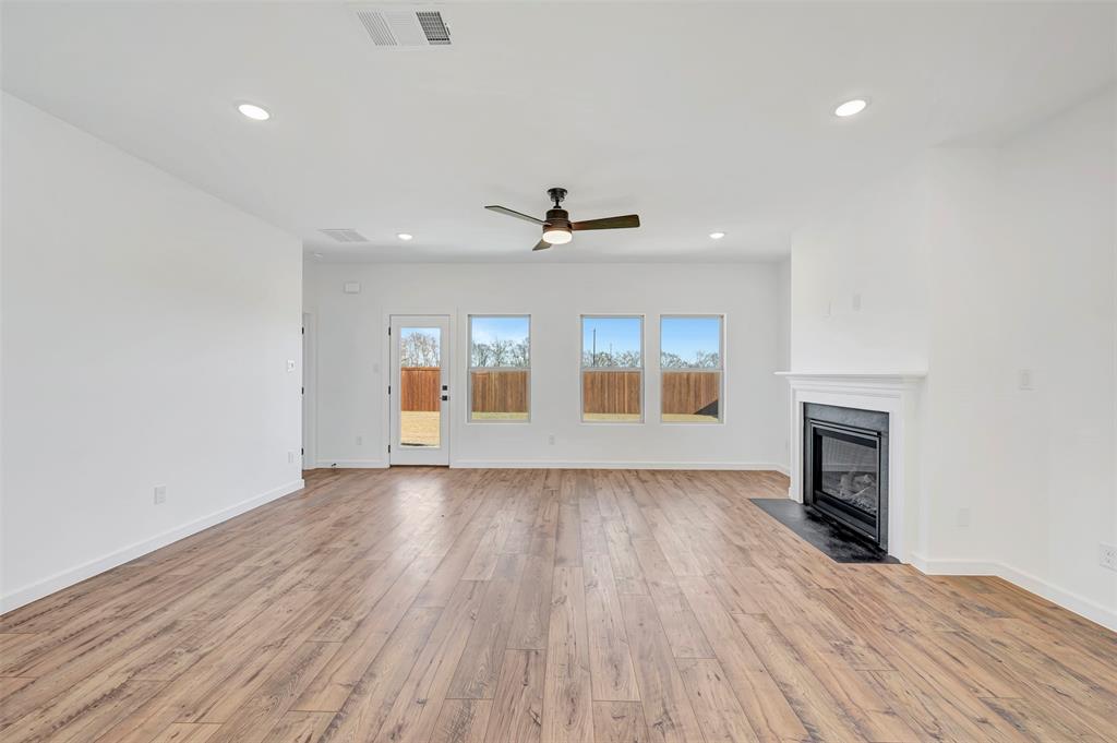 2217 Maple Ridge Drive Van Alstyne, TX 75495 - Photo 8 of 38 an empty room with wooden floor fireplace and windows