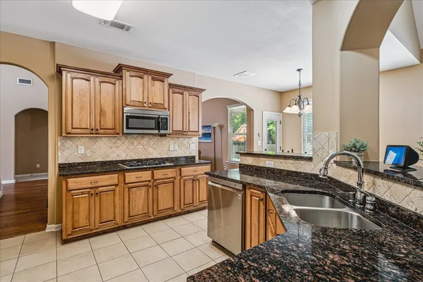 a kitchen with kitchen island granite countertop a sink stove and cabinets