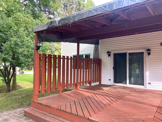 a view of a backyard with table and chairs under an umbrella with a barbeque