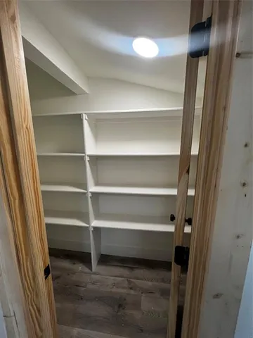 an empty room with wooden floor and entrance