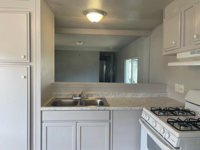 14610 Mono Way, Unit 7 Sonora, CA 95370 - Photo 4 of 15 Kitchen featuring white gas range oven, light countertops, white cabinets, and under cabinet range hood