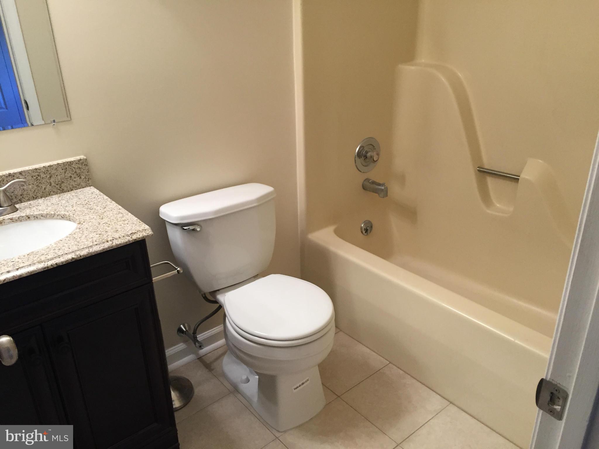 7817 Camp Road Pasadena, MD 21122 - Photo 14 of 30 a white toilet sitting next to a bath tub