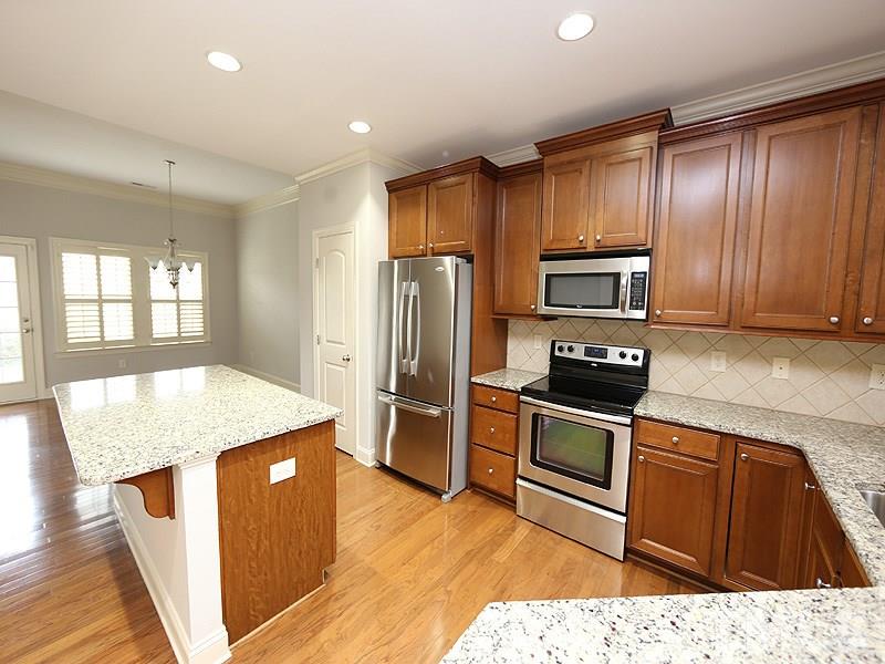 832 Historian Street Raleigh, NC 27603 - Photo 9 of 25 a kitchen with kitchen island granite countertop wooden cabinets a refrigerator oven a sink and dishwasher