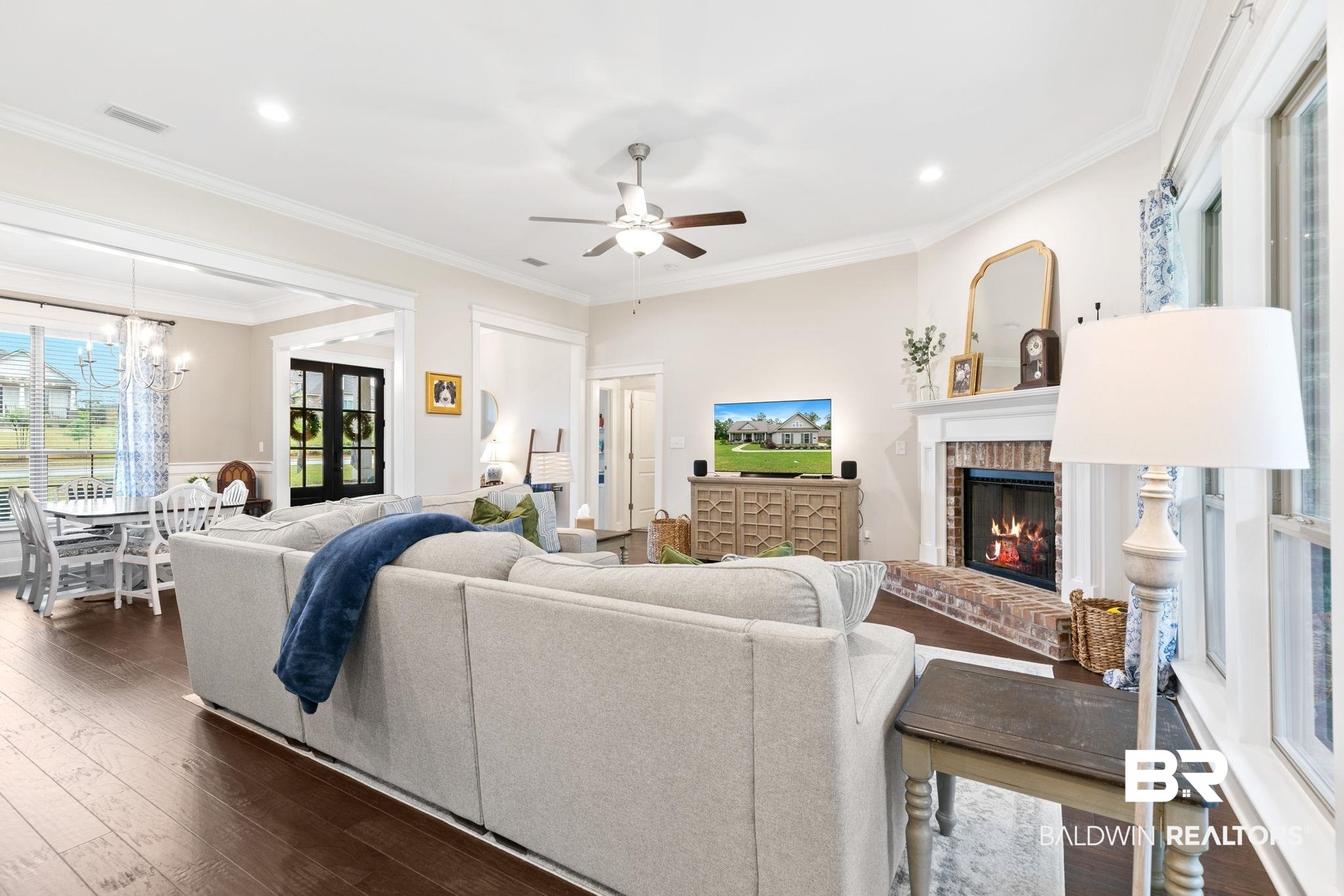13233 Ibis Boulevard Daphne, AL 36527 - Photo 8 of 100 Spacious living area featuring dark wood-finish flooring, a brick-surround fireplace with a white mantel, ceiling fan, recessed lighting, and large windows
