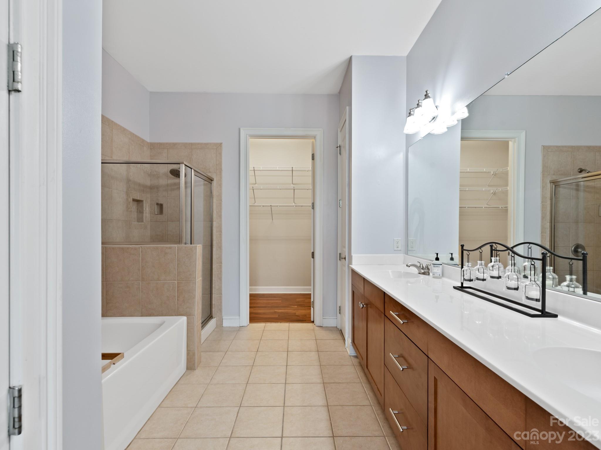5425 Closeburn Road, Unit 201 Charlotte, NC 28210 - Photo 10 of 35 a bathroom with a double vanity sink a large mirror and a bathtub