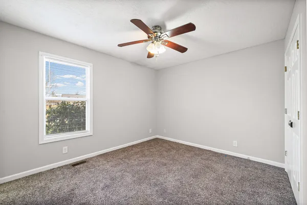 an empty room with fan and windows