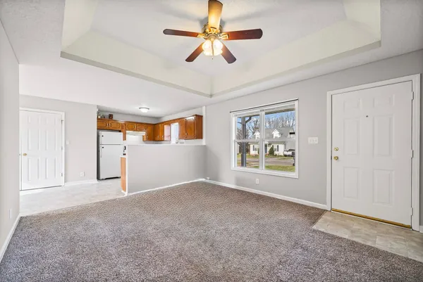 a view of an empty room with window and chandelier fan