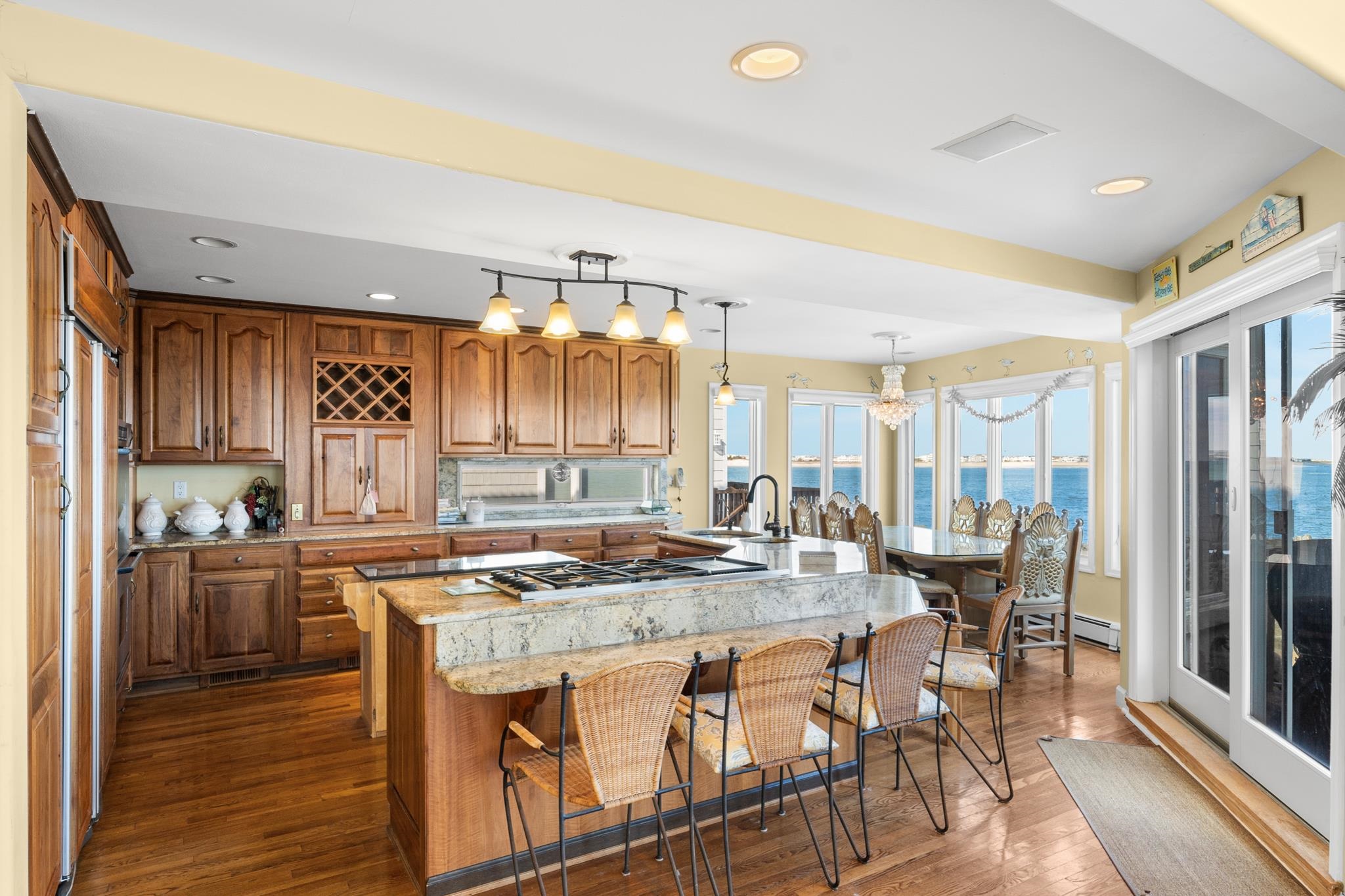 283 6th Street Avalon, NJ 08202 - Photo 11 of 36 a kitchen with stainless steel appliances granite countertop a stove top oven a dining table and chairs with wooden floor