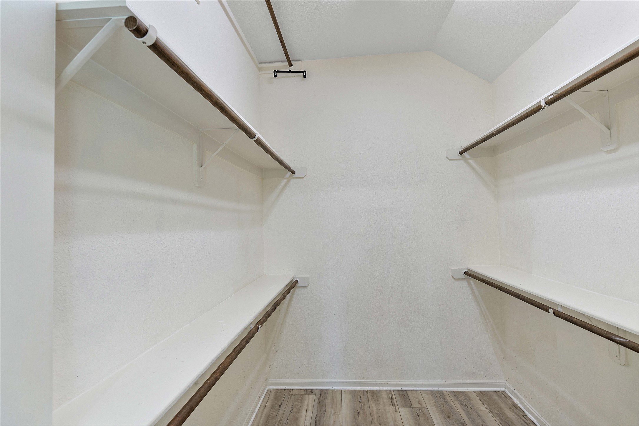 17206 Upper Ridge Lane Humble, TX 77346 - Photo 39 of 50 A spacious primary walk-in closet with multiple shelves and hanging rods, featuring neutral walls and a light wood floor. Perfect for ample storage and organization.