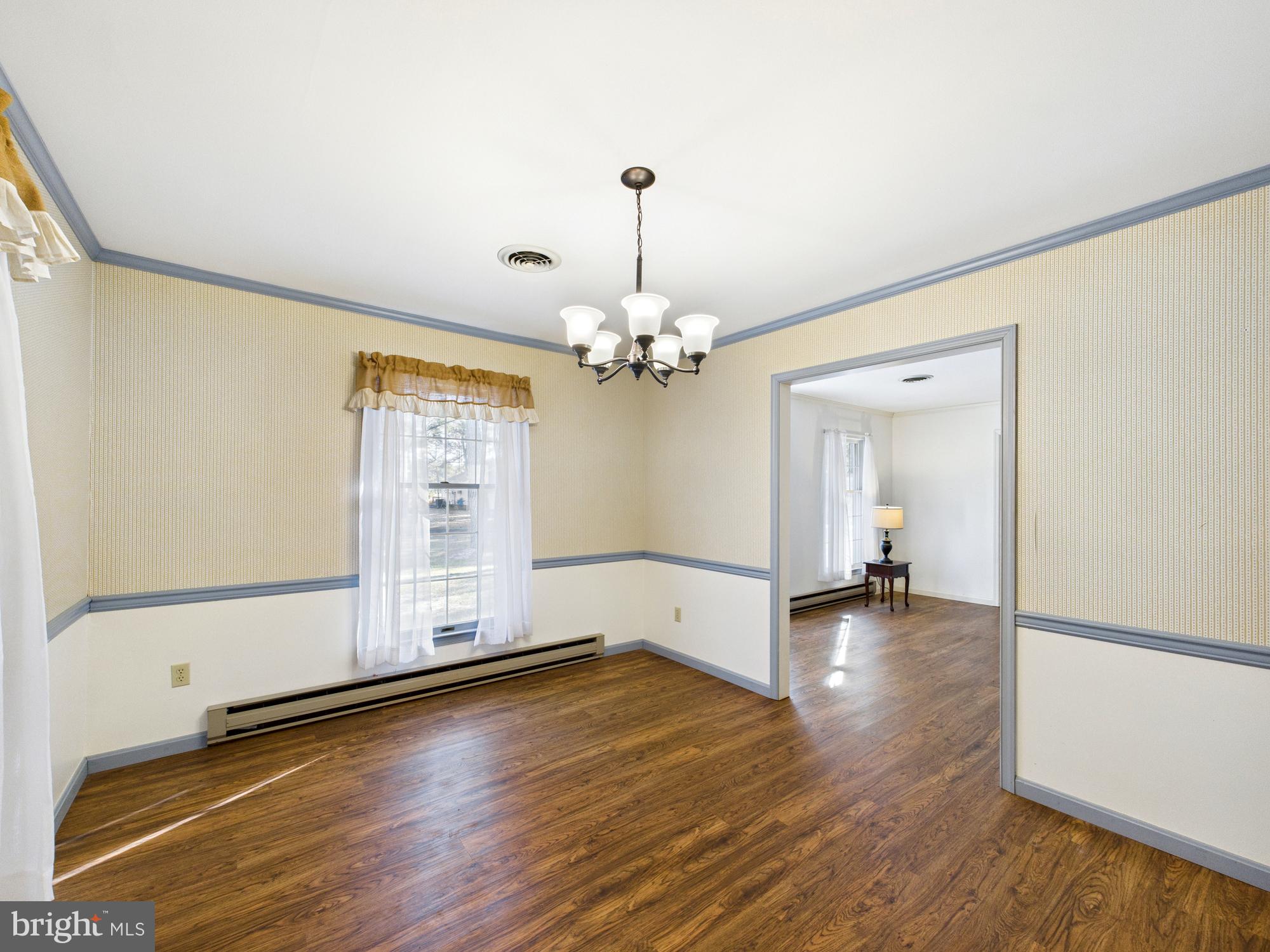 5046 Manokin Road Crisfield, MD 21817 - Photo 21 of 72 an empty room with wooden floor chandelier and windows