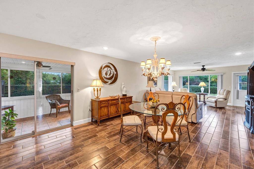 6416 Mercer Road Bradenton, FL 34207 - Photo 8 of 38 a dining room with wooden floor a chandelier a glass table and chairs