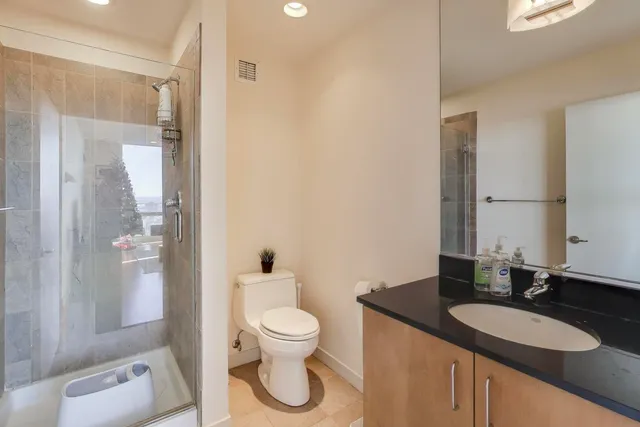 a bathroom with a granite countertop sink a toilet a mirror and shower