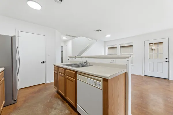 a view of a kitchen with a refrigerator wooden cabinets and a window