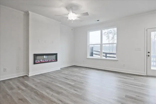 an empty room with wooden floor chandelier fan and windows