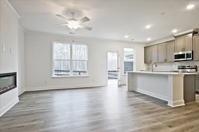 a large kitchen with kitchen island granite countertop a stove a sink a refrigerator and white cabinets with wooden floor