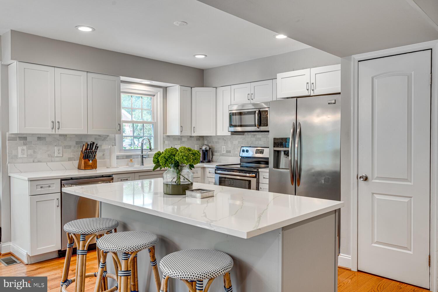 2091 Cobblestone Lane Reston, VA 20191 - Photo 7 of 33 a kitchen with stainless steel appliances a sink a refrigerator and white cabinets with wooden floor