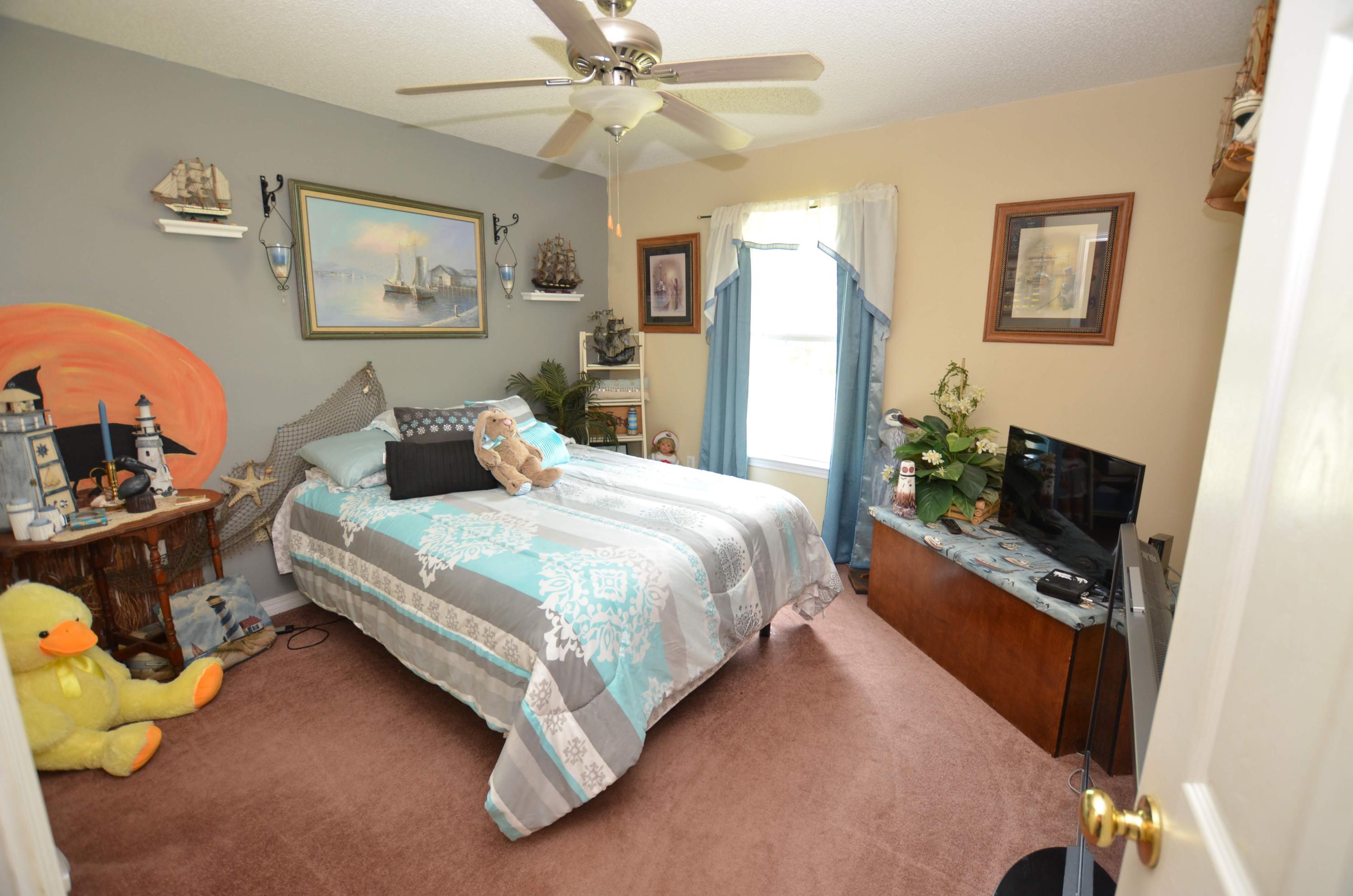 715 Ridge Lake Road Crestview, FL 32536 - Photo 8 of 14 a bedroom with a bed dresser and a flat tv screen