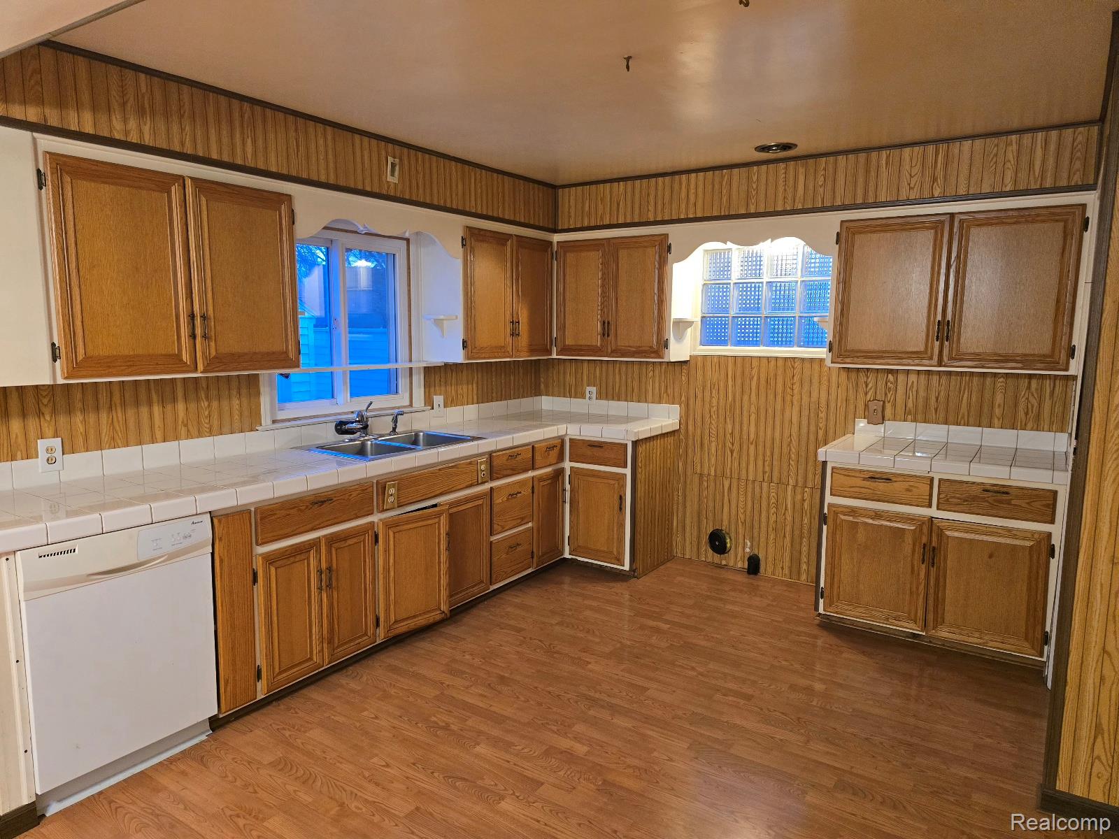 803 Commonwealth Avenue Flint, MI 48503 - Photo 6 of 15 Kitchen with tile counters, wood finish cabinetry, white dishwasher, dark wood-style flooring, and wooden walls