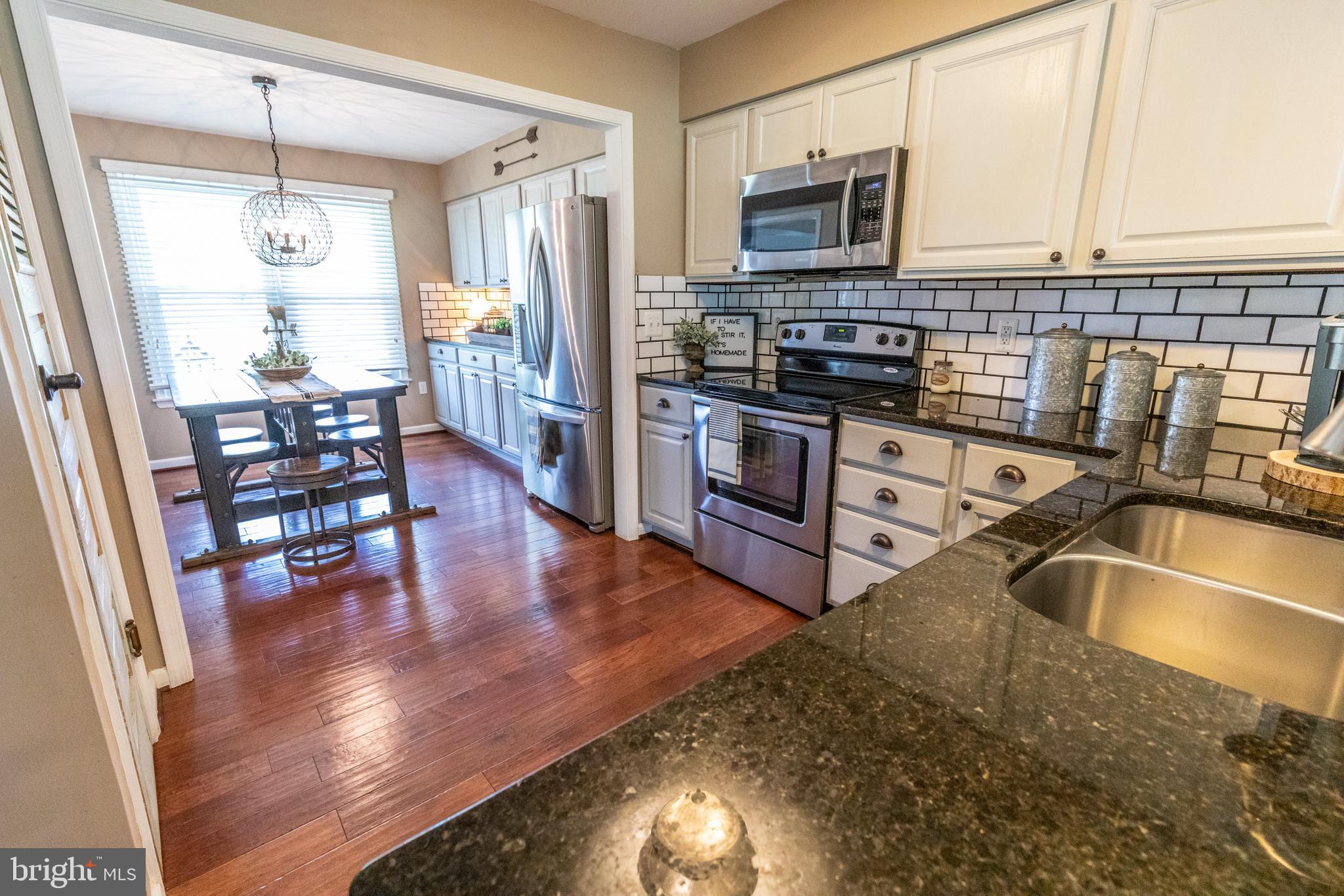 193 Quail Run Road Summit Point, WV 25446 - Photo 23 of 72 a kitchen with stainless steel appliances granite countertop a stove top oven a sink a dining table and chairs with wooden floor
