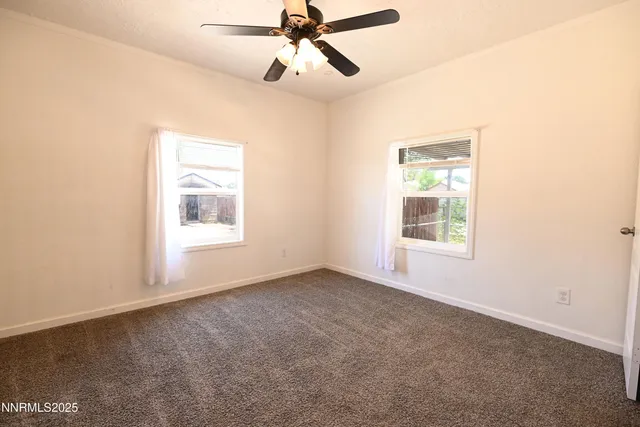an empty room with a ceiling fan and carpet