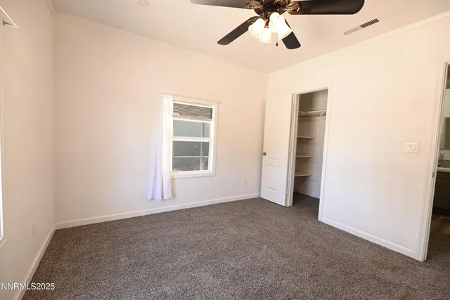 an empty room with ceiling fan and window