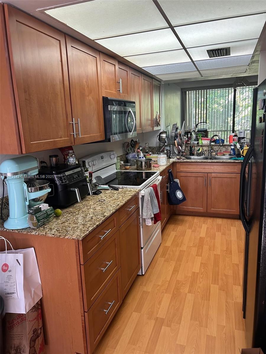 2811 Southwest 87th Terrace, Unit 1210 Davie, FL 33328 - Photo 6 of 8 a kitchen with stainless steel appliances granite countertop a sink stove and cabinets