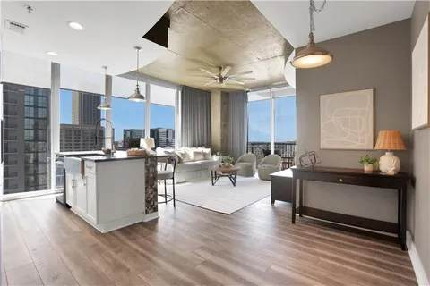a living room with couches kitchen view and a chandelier