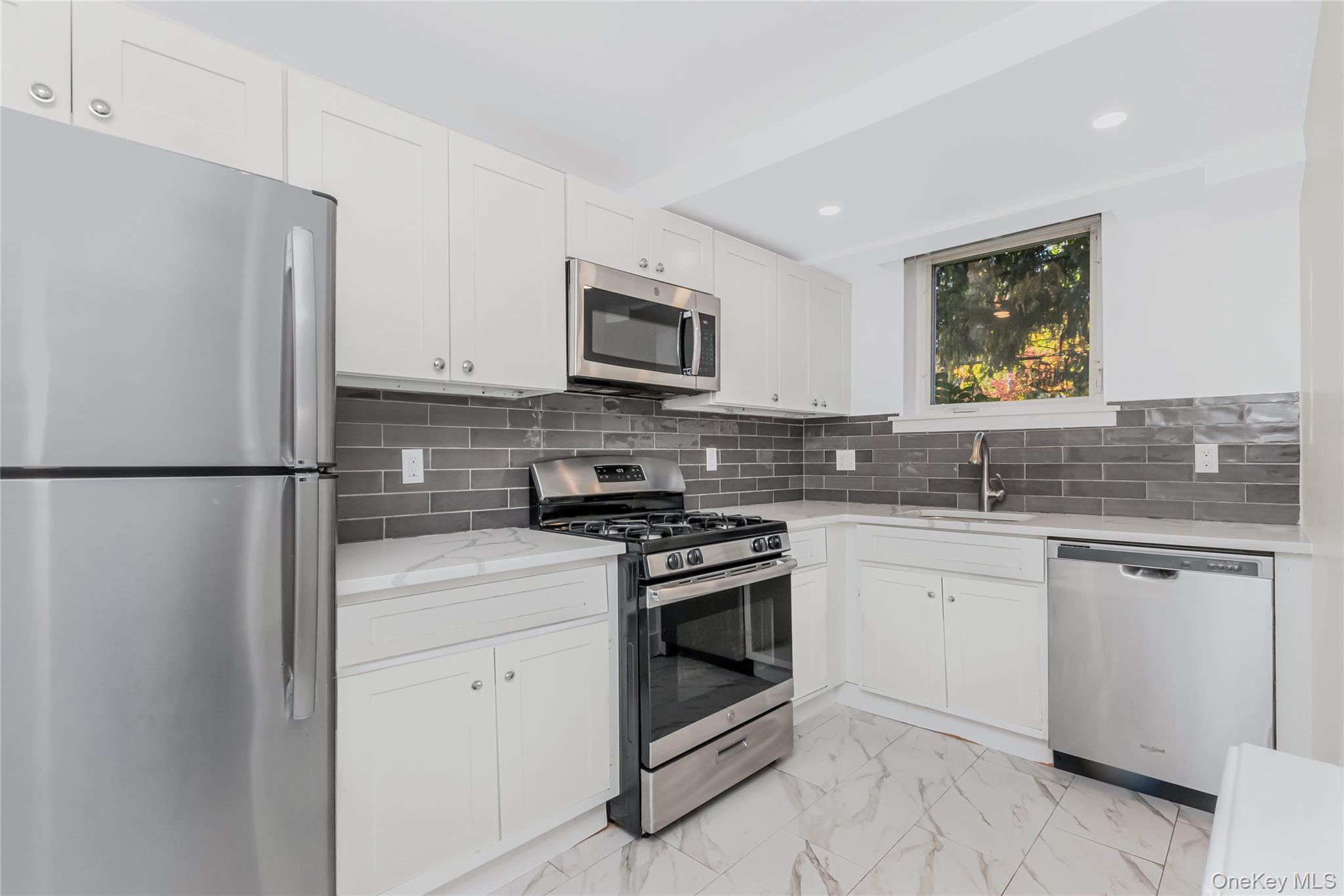 59 Oregon Avenue Bronxville, NY 10708 - Photo 7 of 26 Kitchen featuring appliances with stainless steel finishes, tile backsplash, white cabinetry, quartz counter tops, tile flooring, and recessed lighting