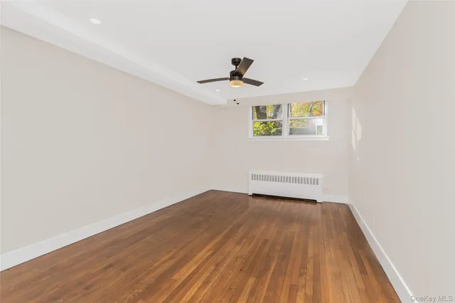 an empty room with wooden floor ceiling fan and windows