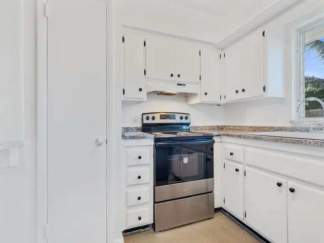 a bathroom with a granite countertop sink vanity and a refrigerator