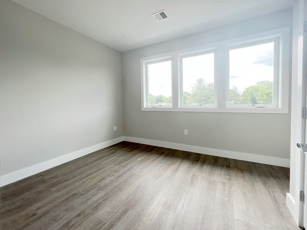 80 Bridge Street, Unit 308 Dedham, MA 02026 - Photo 12 of 19 an empty room with wooden floor and windows