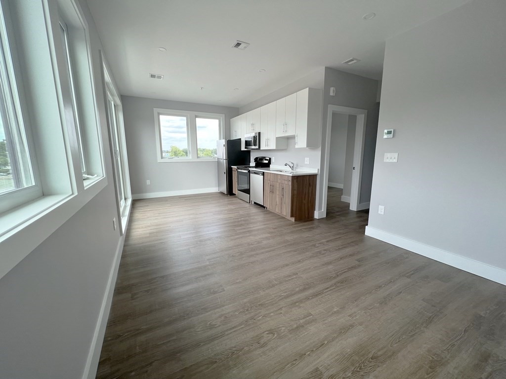 80 Bridge Street, Unit 308 Dedham, MA 02026 - Photo 7 of 19 a view of a kitchen with wooden floor and electronic appliances