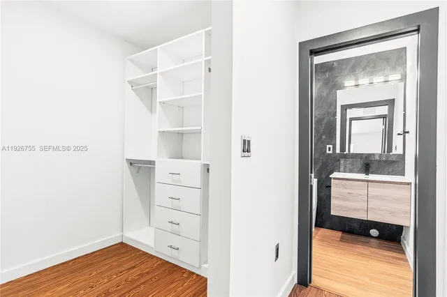 a view of walk in closet with cabinet and wooden floor
