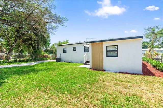 a backyard of a house with plants and large tree