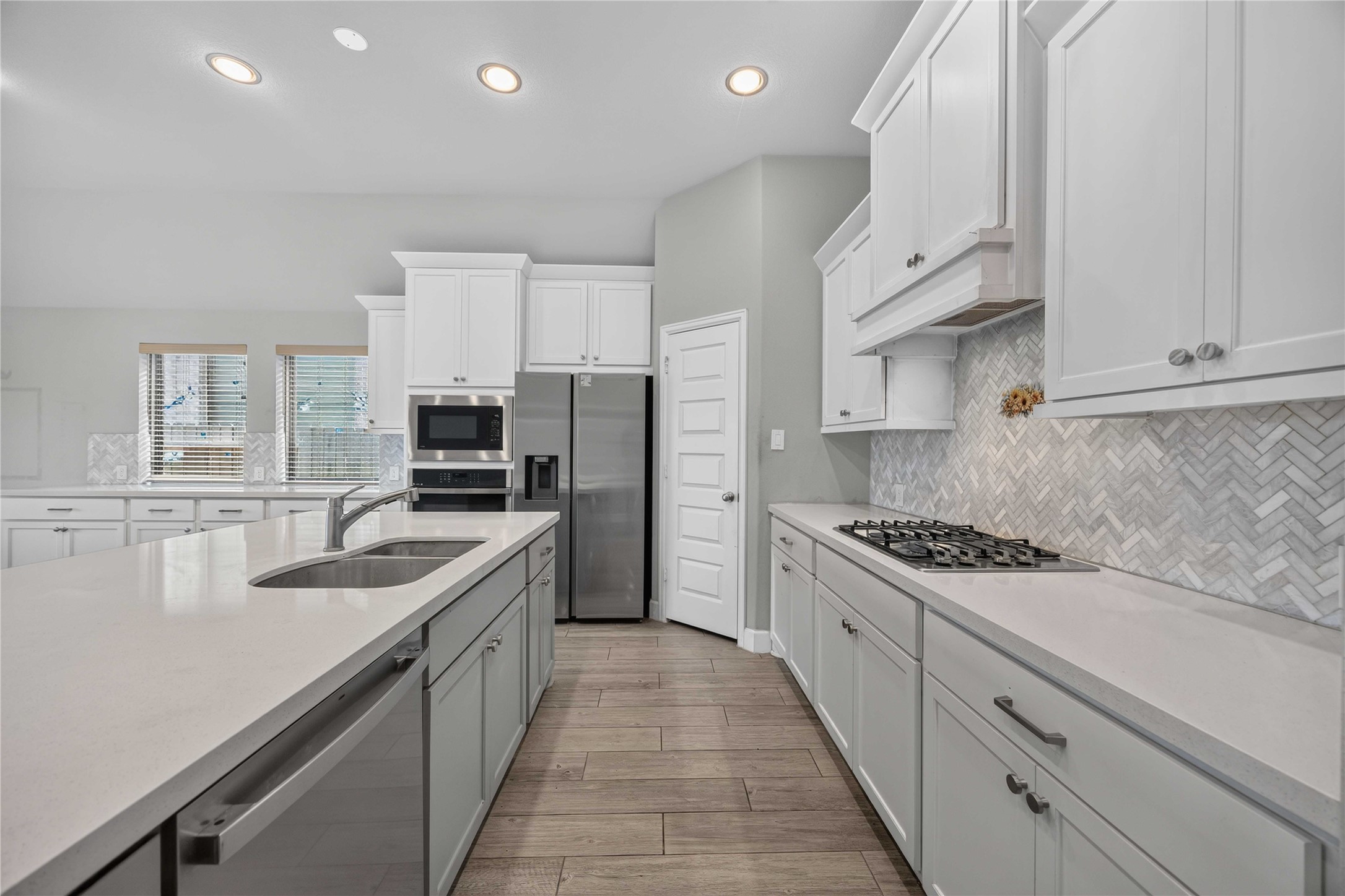 4333 Arbor Crest Lane Manvel, TX 77578 - Photo 10 of 40 A dream kitchen centered around a massive center island, lined with crisp white cabinetry, premium glossy countertops, and a stylish herringbone tile backsplash.
