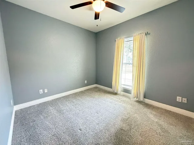 an empty room with ceiling fan and window