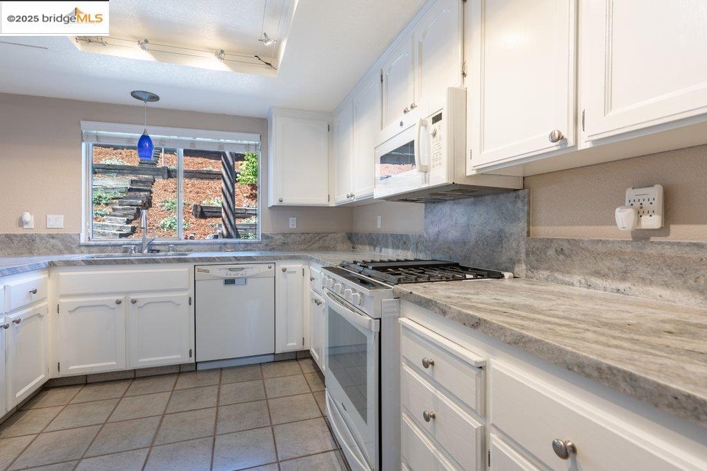 1003 Linda Vista Way Rio Vista, CA 94571 - Photo 13 of 60 Kitchen featuring white appliances, white cabinetry, light countertops, and decorative light fixtures