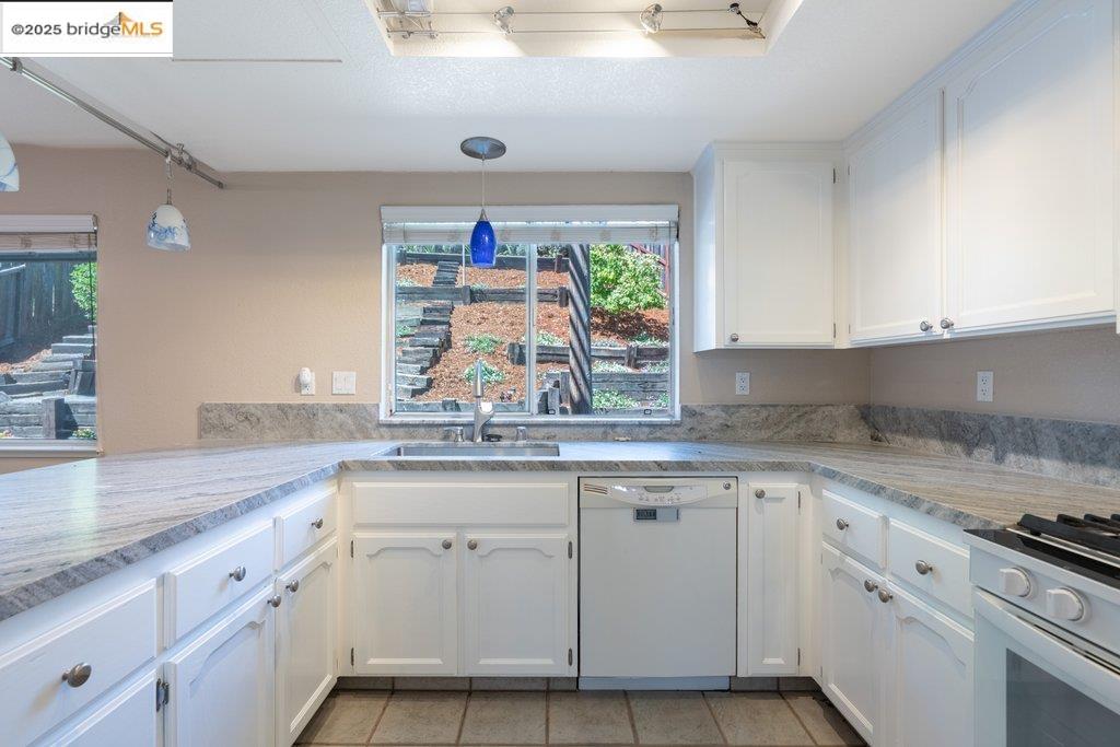 1003 Linda Vista Way Rio Vista, CA 94571 - Photo 14 of 60 Kitchen with dishwasher, white cabinets, stainless steel gas range oven, hanging light fixtures, and light tile patterned floors