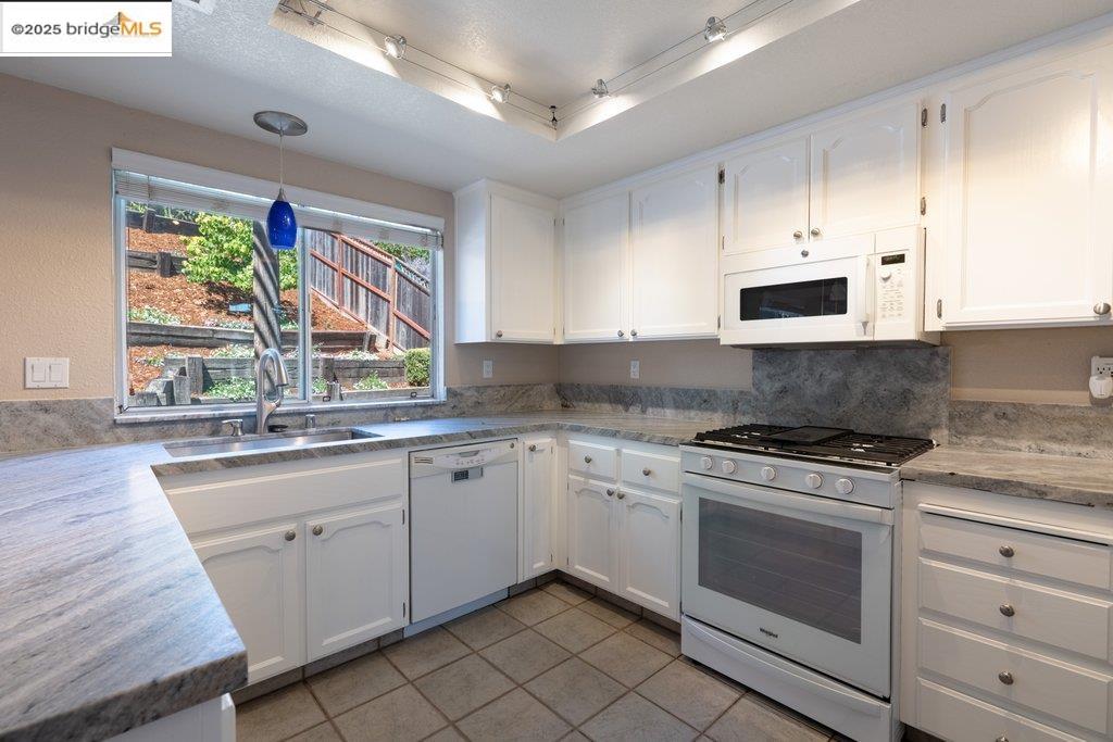 1003 Linda Vista Way Rio Vista, CA 94571 - Photo 15 of 60 Kitchen featuring white appliances, white cabinets, light tile patterned floors, rail lighting, and pendant lighting
