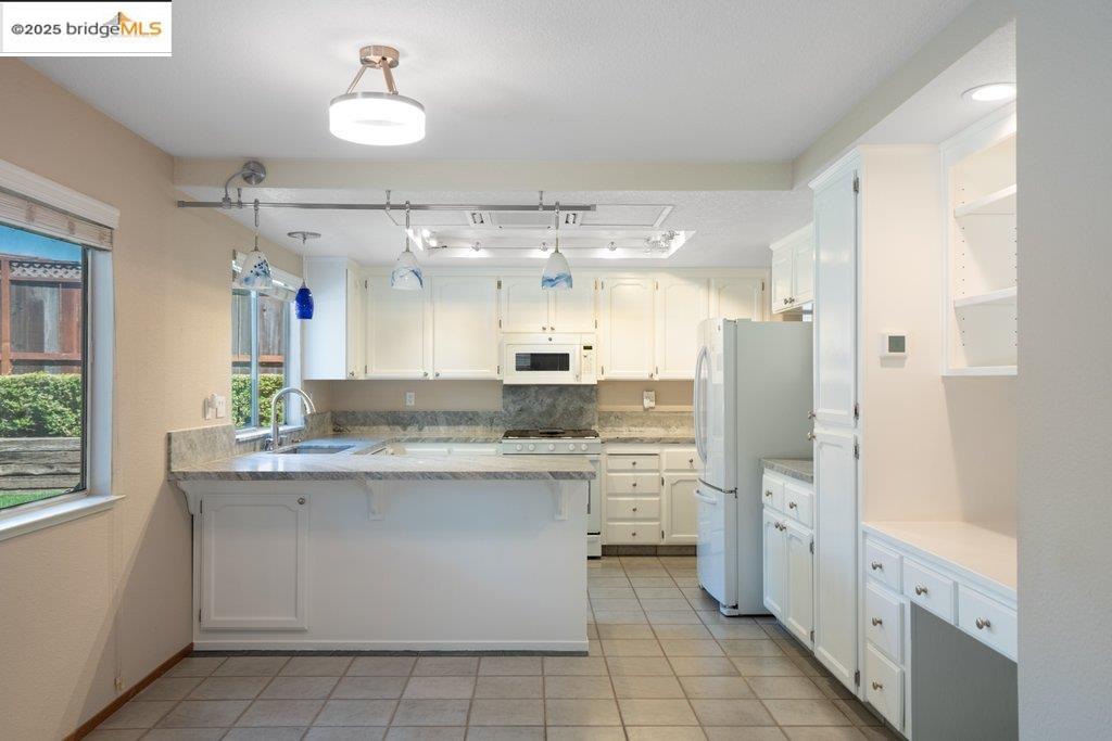 1003 Linda Vista Way Rio Vista, CA 94571 - Photo 18 of 60 Kitchen featuring a peninsula, white appliances, white cabinets, and light tile patterned floors