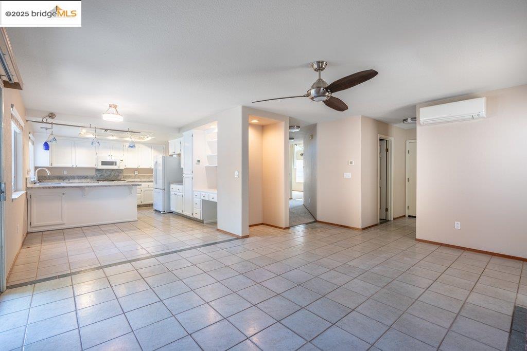 1003 Linda Vista Way Rio Vista, CA 94571 - Photo 21 of 60 Unfurnished living room featuring light tile patterned floors, an AC wall unit, and ceiling fan